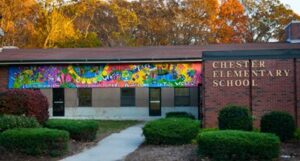 Colorful mural on elementary school exterior wall with autumn trees.