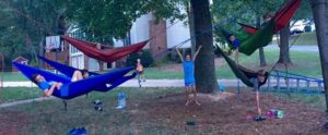 Children playing and swinging on tree hammocks in a backyard.