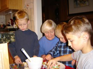 Three boys and an older woman engaged in a craft activity indoors.