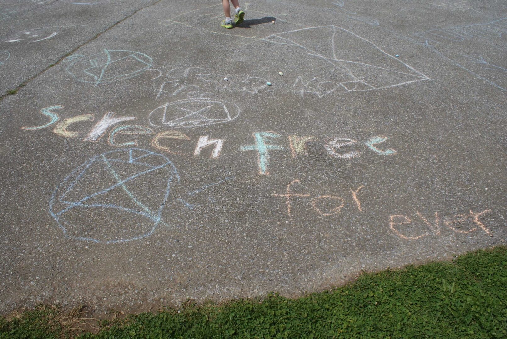 Chalk messages and drawings on pavement with peace symbols and 'freedom' text.