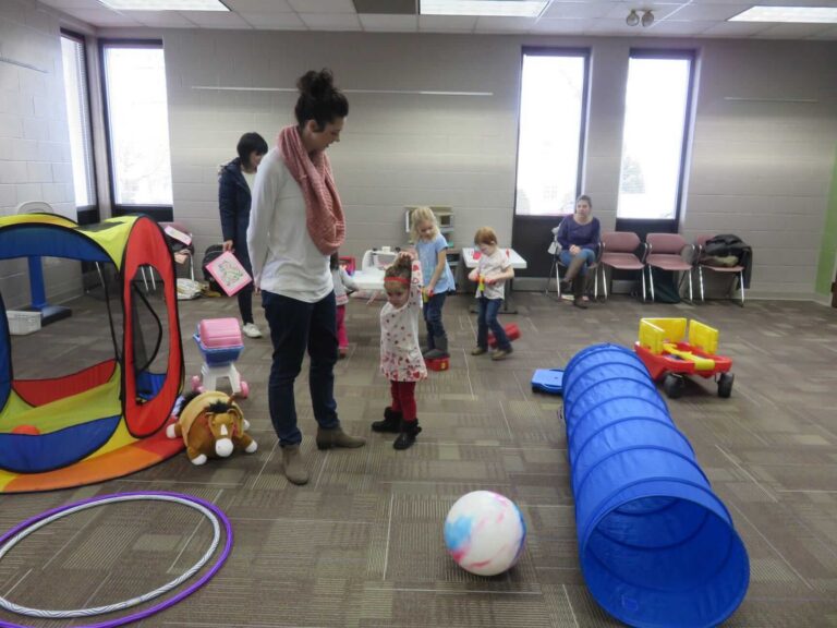 Children and an adult playing with toys in a room.