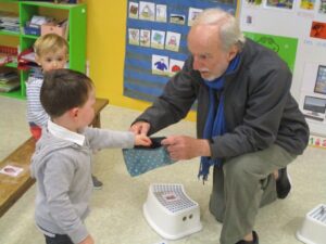 Jacques Brodeur crouching and speaking to child in classroom