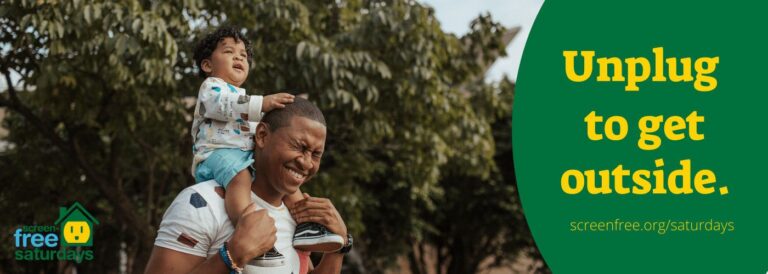 Father with child on shoulders outdoors.