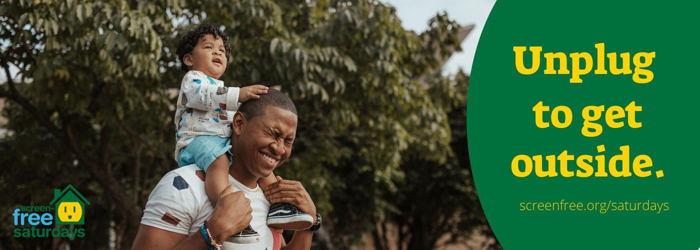Father with child on shoulders outdoors.