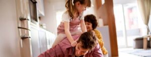A father playing with his two young children indoors.