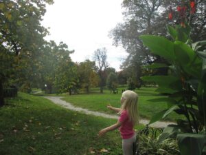 A young girl walking along a winding path in a lush park.