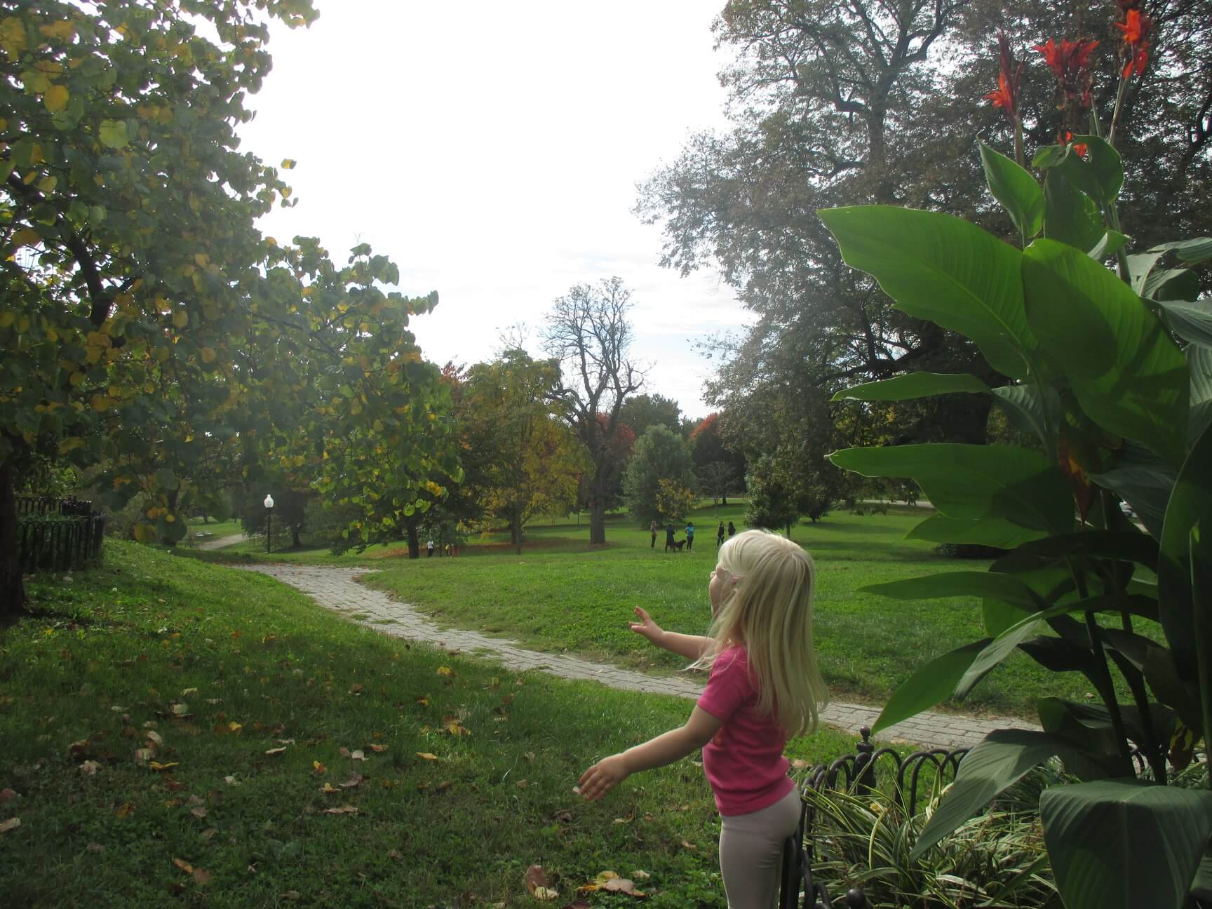 A young girl walking along a winding path in a lush park.