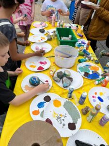 Children painting rocks with colorful designs at a craft table.