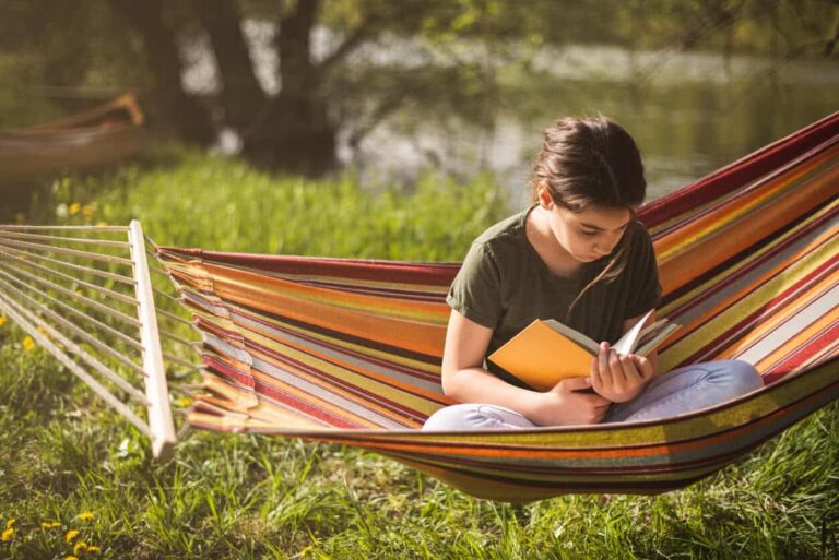 Woman reading a book while relaxing in a hammock outdoors.