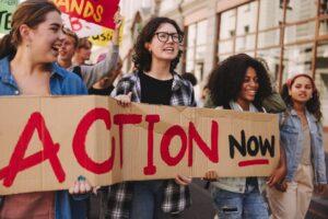 Protesters holding a large sign reading 'Action Now' during a demonstration.