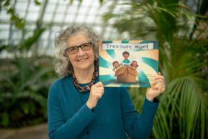 A woman holding the book 'Treasure Hunt' and smiling.