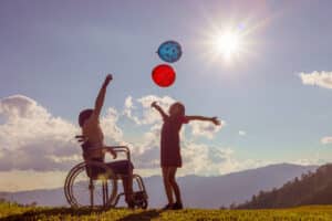 Two boys playing catch outdoors, one in a wheelchair.